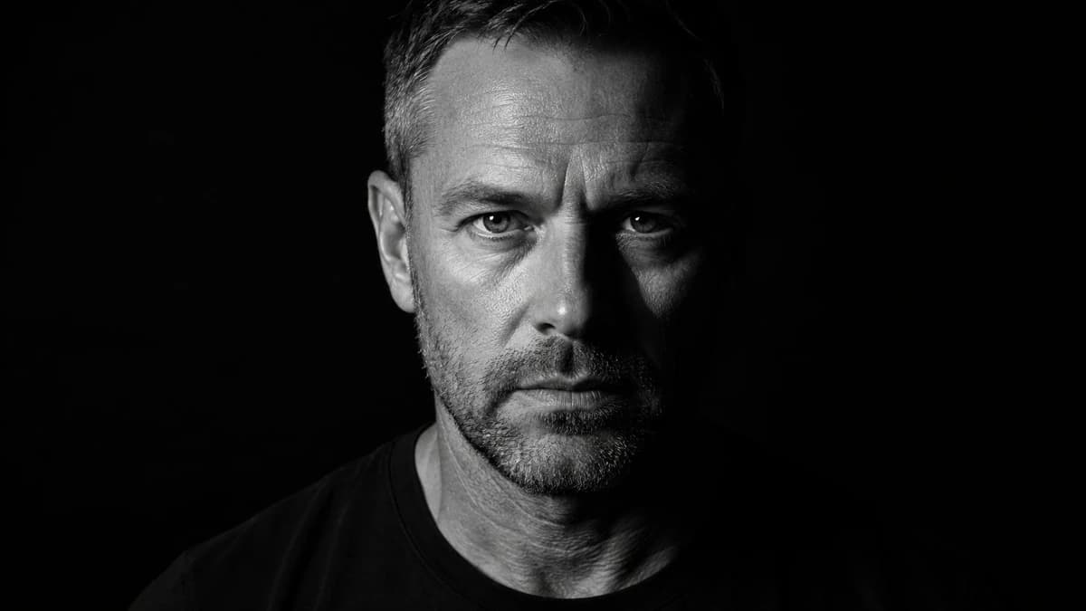 Photorealistic black and white cinematic portrait of a rugged middle aged...