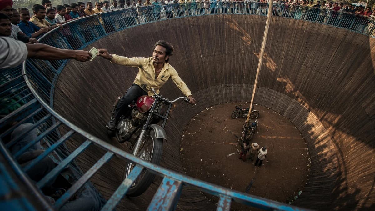 A cinematic wide-angle documentary photograph of a daring motorcycle stun...