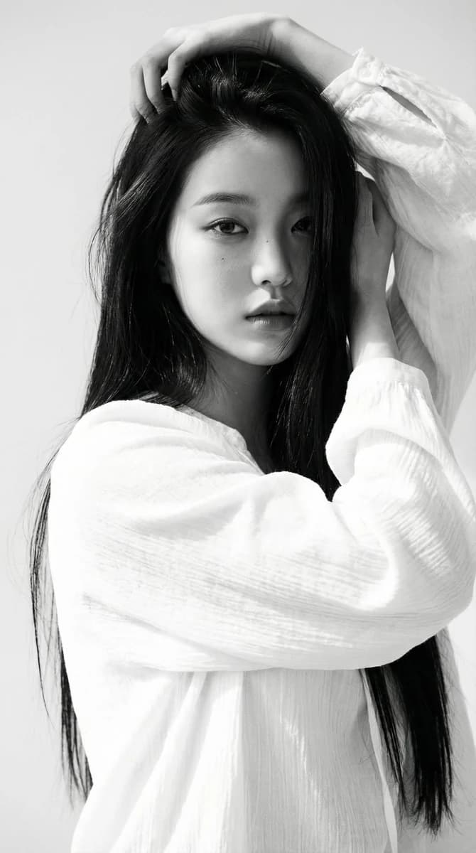 Black-and-white portrait of a young woman with long straight dark hair, w...